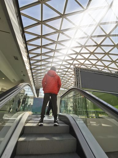 A vertical shot of the glass ceiling of a modern building captured from the escalator