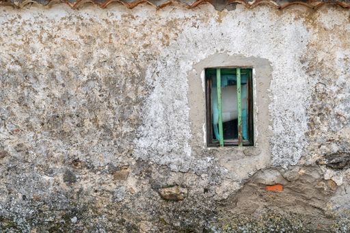 A closeup shot of a small window on a very old house in a village