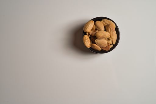 A top view of sunflower seeds in a small black bowl on white table