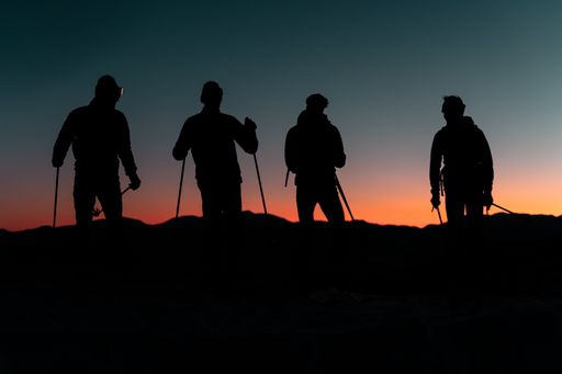 The shadows of a group of friends on a mountain during the sunset
