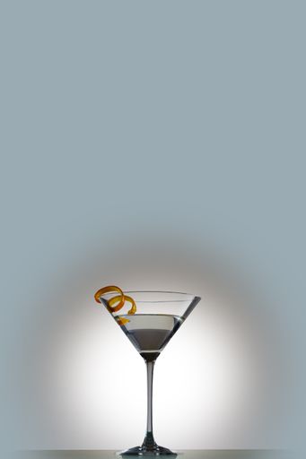 A vertical shot of a martini in a cocktail glass served with orange peel isolated on a white background
