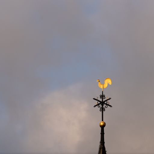 The golden rooster vane against the gray sky.