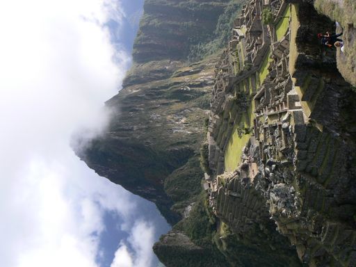 A vertical shot of clouds hovering over the big tall mountains in Machu Picchu, Peru