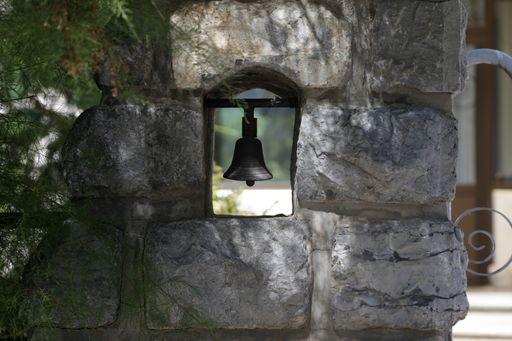 A close-up shot of a small bell that is affixed to a traditional, aged stone wall