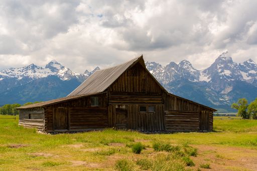 A natural view of a wooden house in the middle of a field in the countryside