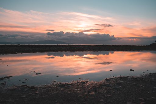 The reflection of some clouds at a water puddle during sunrise