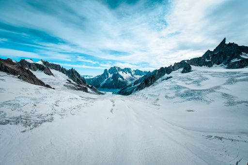 A beautiful wide shot of ruth glaciers covered in snow under a blue sky with white clouds