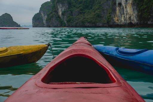 A close shot of a red canoe on the water with a mountain in the distance