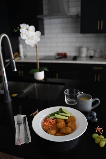A vertical shot of fresh tasty chicken nuggets with cucumbers and carrots on a kitchen table