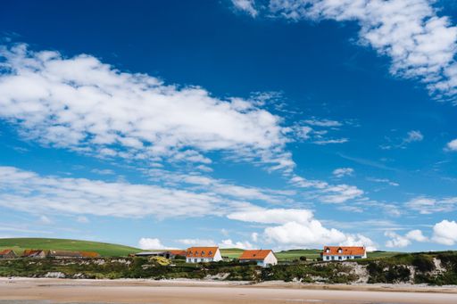 A beautiful shot of houses in a grassy field under a blue cloudy sky in  France