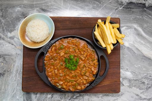 A top view of a plate of Turkish meat saute on a board with rice and french fries
