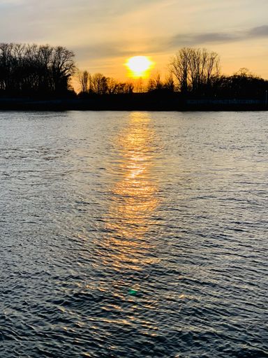 A beautiful view of a sunset over the lake in a park