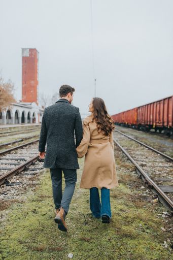 A closeup of a couple walking near the railway