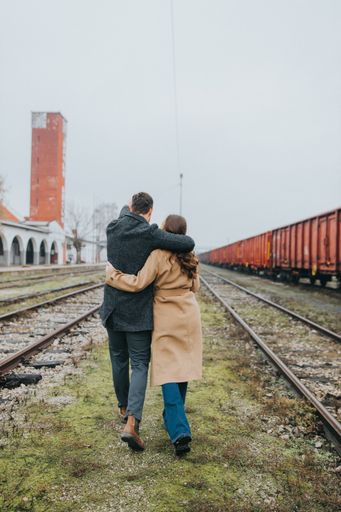 A closeup of a couple walking near the railway