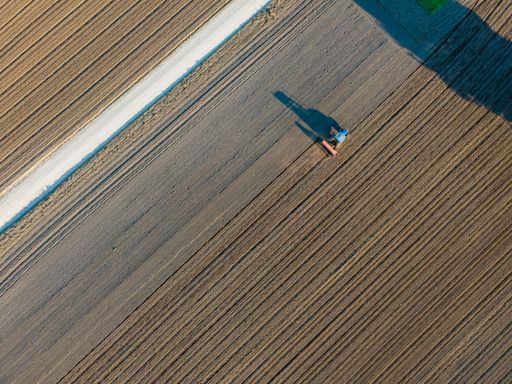 An aerial view of a tractor working in an agricultural field at sunset in Udine, Friuli Venezia Giulia, Italy