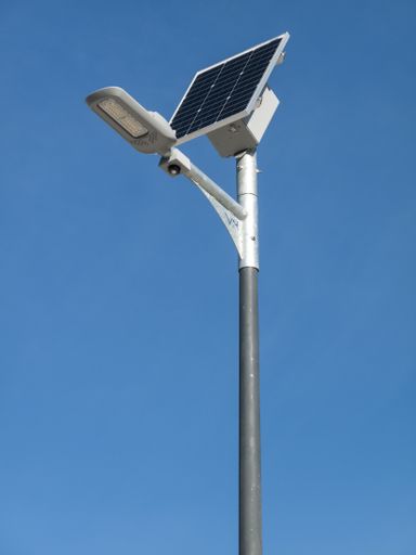 A vertical low angle shot of a street lamp with a solar energy panel under the blue sky