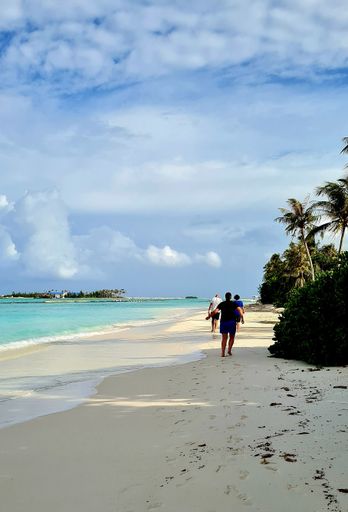 A vertical shot of tourists walking in a sandy beach in Maldives