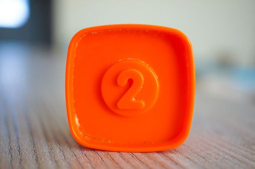 A closeup shot of an orange plastic square-shaped toy with number two on a center