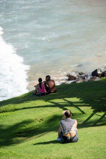 A vertical shot of backside of several people enjoying the view of Farol da Barra beach in Salvador, Bahia, Brazil