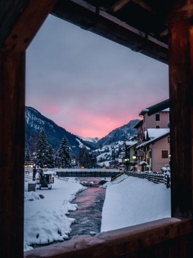 A vertical shot of a breathtaking view out of the window of a house in snowy mountains