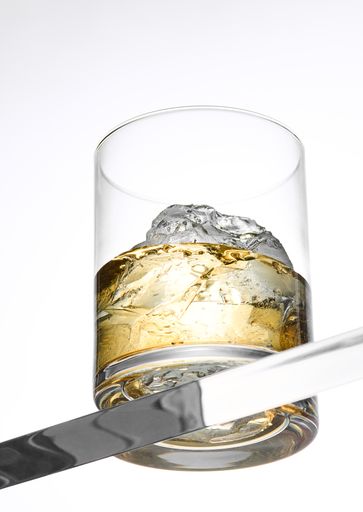 A vertical low angle shot of a glass of whiskey isolated on a white background