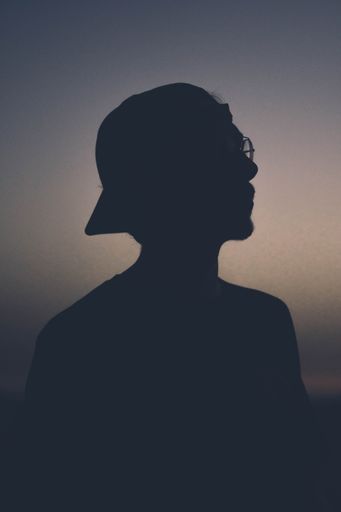 A silhouette of a man wearing glasses looking right