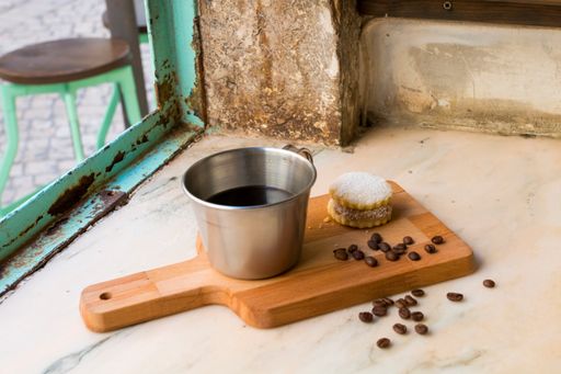 A closeup of a coffee mug with a delicious cookie on a board
