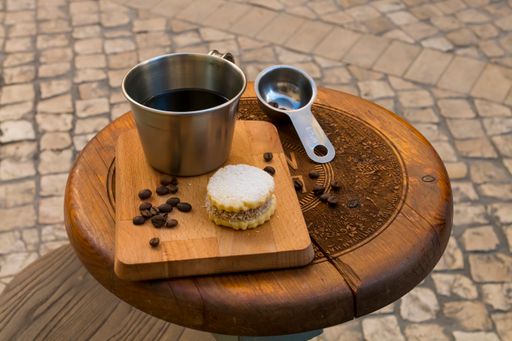 A closeup of a coffee mug with a delicious cookie on a board