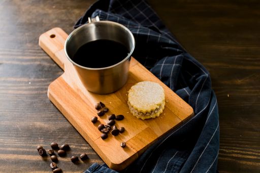 A closeup of a coffee mug with a delicious cookie on a board