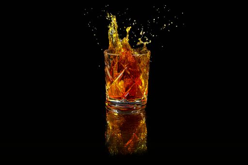 A closeup of whiskey splash in the whiskey glass on black background