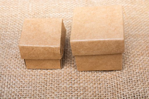 A closeup view of a small and large box made of cardboard placed on a brown surface