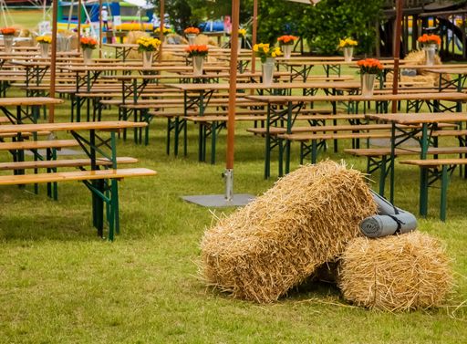 A picnic area with tables and umbrellas, bales of hay in the foreground