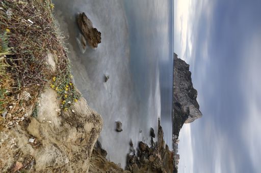 A breathtaking view of the rock formations at the beach against blue sky with clouds