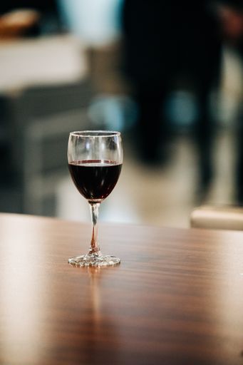 A vertical shot of a glass of white on a wooden table under the light