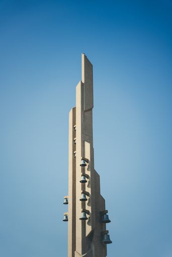 A vertical shot of the tall building with bells on the side with clear sky in the background
