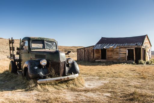An old abandoned car and a wooden building in a rural area