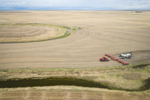 A bird's-eye view of a farming field and seeding machine during daytime