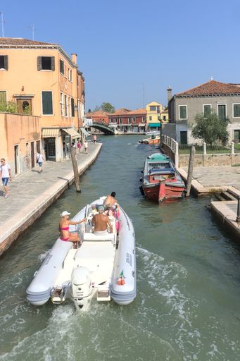 A vertical shot of a tourism boat on the canal Murano island in Venice, Italy