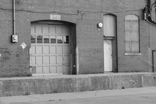 A grayscale shot of damaged doors on an old warehouse