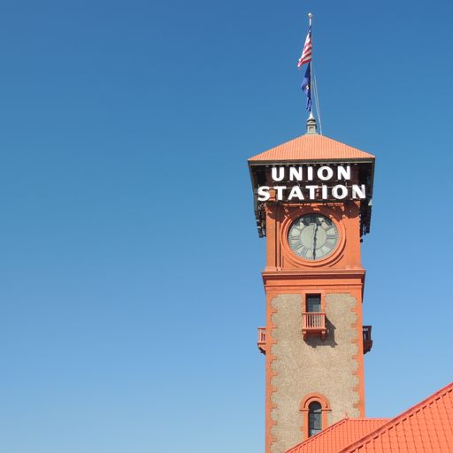 A vertical shot of the old American Railroad Train Station Clock Tower and United States Flag