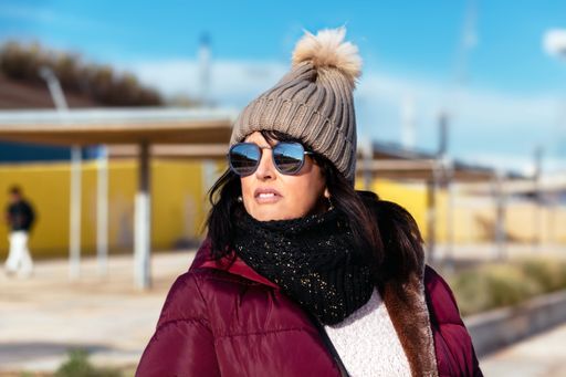portrait of a woman with sunglasses and wool cap on a sunny autumn day walking in the city