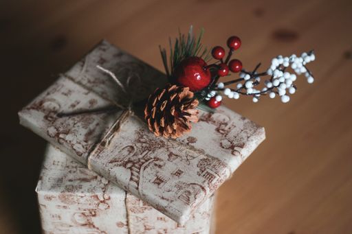 A closeup shot of a Christmas gift boxes decorated with fir branches and red berries on a wooden table