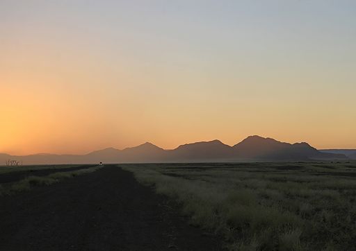 Headlights in the sunrise at dawn among the dunes of the Namibian Sand Sea. Guides bring tourist here at 5 a.m.