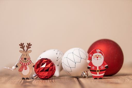 A closeup shot of colorful Christmas ornament balls with small wooden deer and Santa Claus figurines on the table