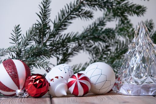 A closeup shot of colorful Christmas ornaments with a Christmas tree branches on the background