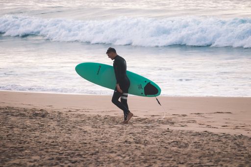 A surfer walking on the beach holding a surfboard
