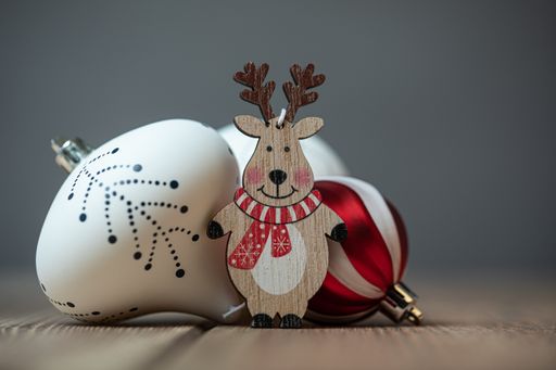 A closeup shot of a small wooden deer figurine with ball ornaments on the table under the lights