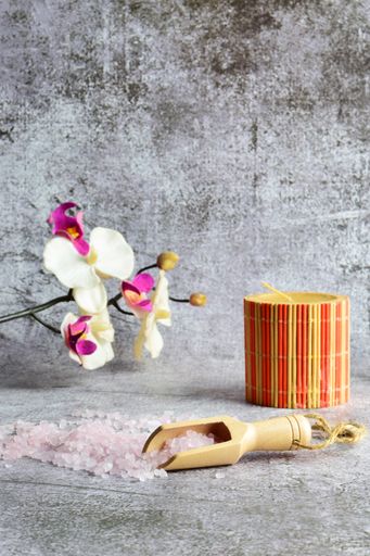 Pink Himalayan salt with a wooden spoon, a bowl, and flowers