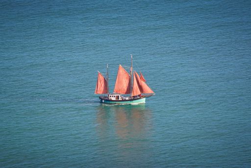The Brian Boru wooden hulled and traditionally rigged Gaff Ketch. Sailing vessel with orange sails seen from above on the East coast of Ireland.