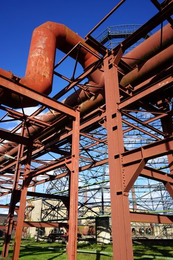 A vertical shot of steel construction with rusty pipes against a blue background